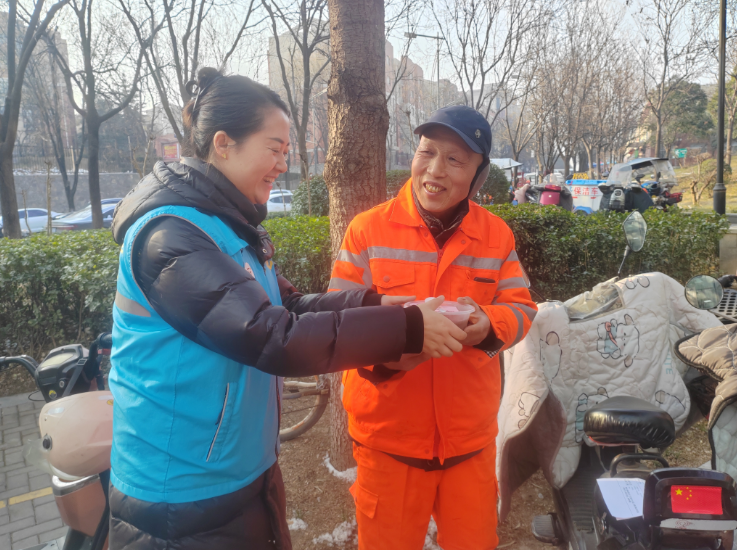 社区工作人员将打包好的腊八粥送到保洁人员手中