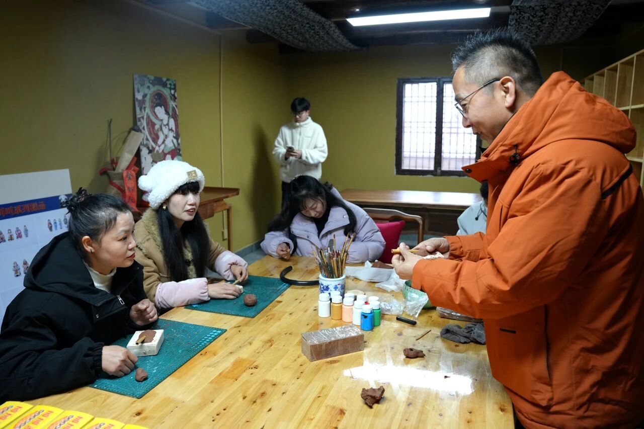 在泥叫叫工作坊,游客跟着鱼化“泥叫叫”第五代传承人杨帆(右一)制作“泥叫叫”。(本文图片由高文亚拍摄)